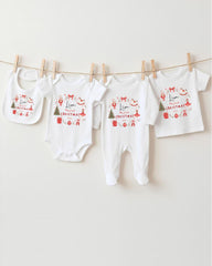 A row of four white baby clothes with Christmas-themed designs hanging on a clothesline.