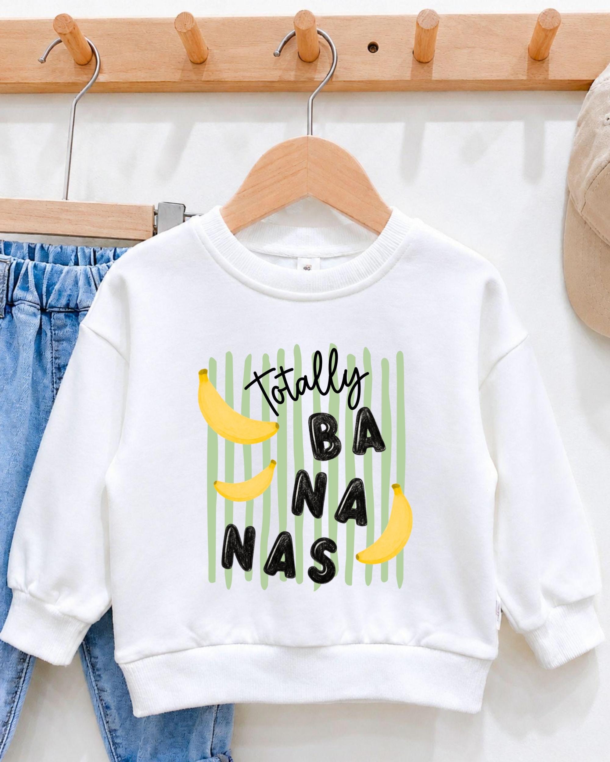 A white sweatshirt with a playful graphic design featuring bananas and the text "Totally BANANA" printed on it.
