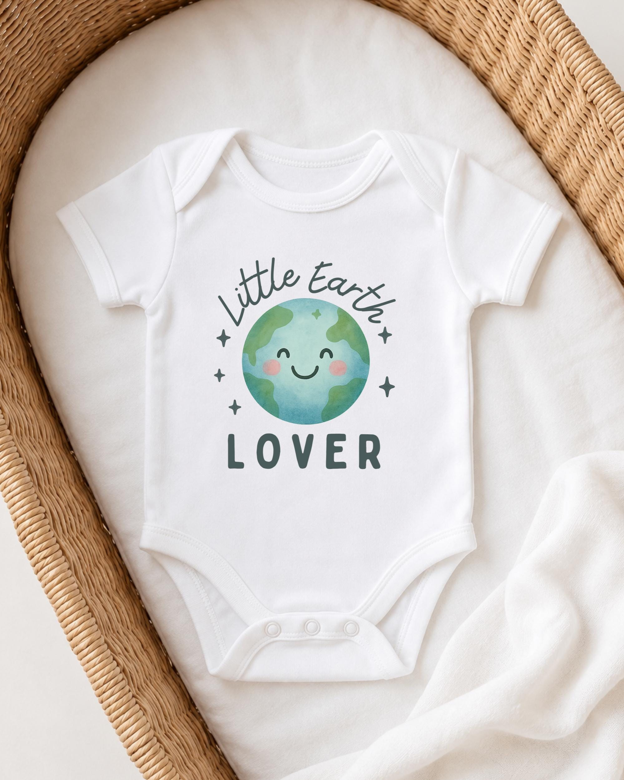 A white onesie with a cartoon image of the Earth and the text "Little Earth Lover" printed on it, placed in a woven basket.