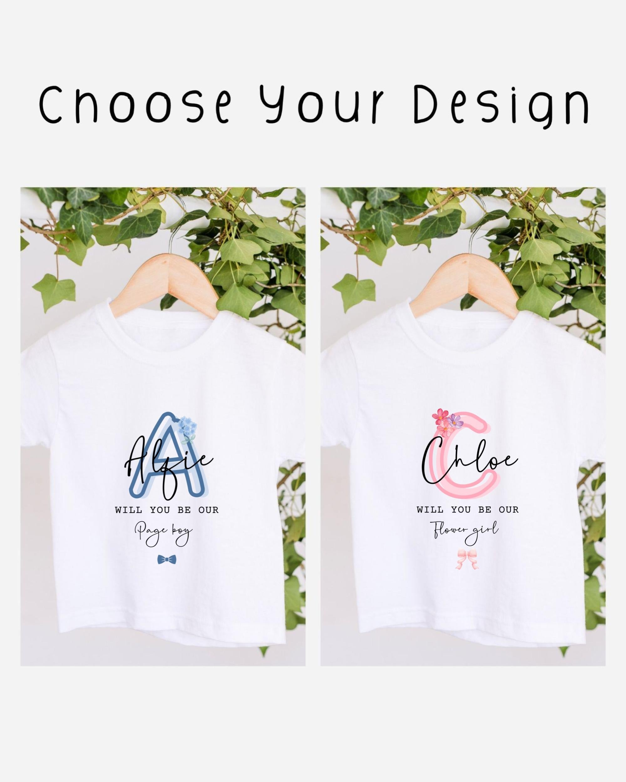 two white t-shirts hanging on a wooden hanger, each with a personalized message printed on them. The messages read "Will you be our Page boy" and "Will you be our Flower girl", suggesting that the t-shirts are intended as gifts or souvenirs for someone named Page boy and Flower girl.
