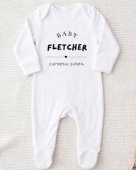A white onesie with the text "BABY FLETCHER COMING SOON" printed on it.