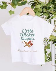 A white t-shirt with a graphic design featuring a cricket bat and ball, along with the text "Little Wicket Keeper" and "Mahmmed" printed on it.