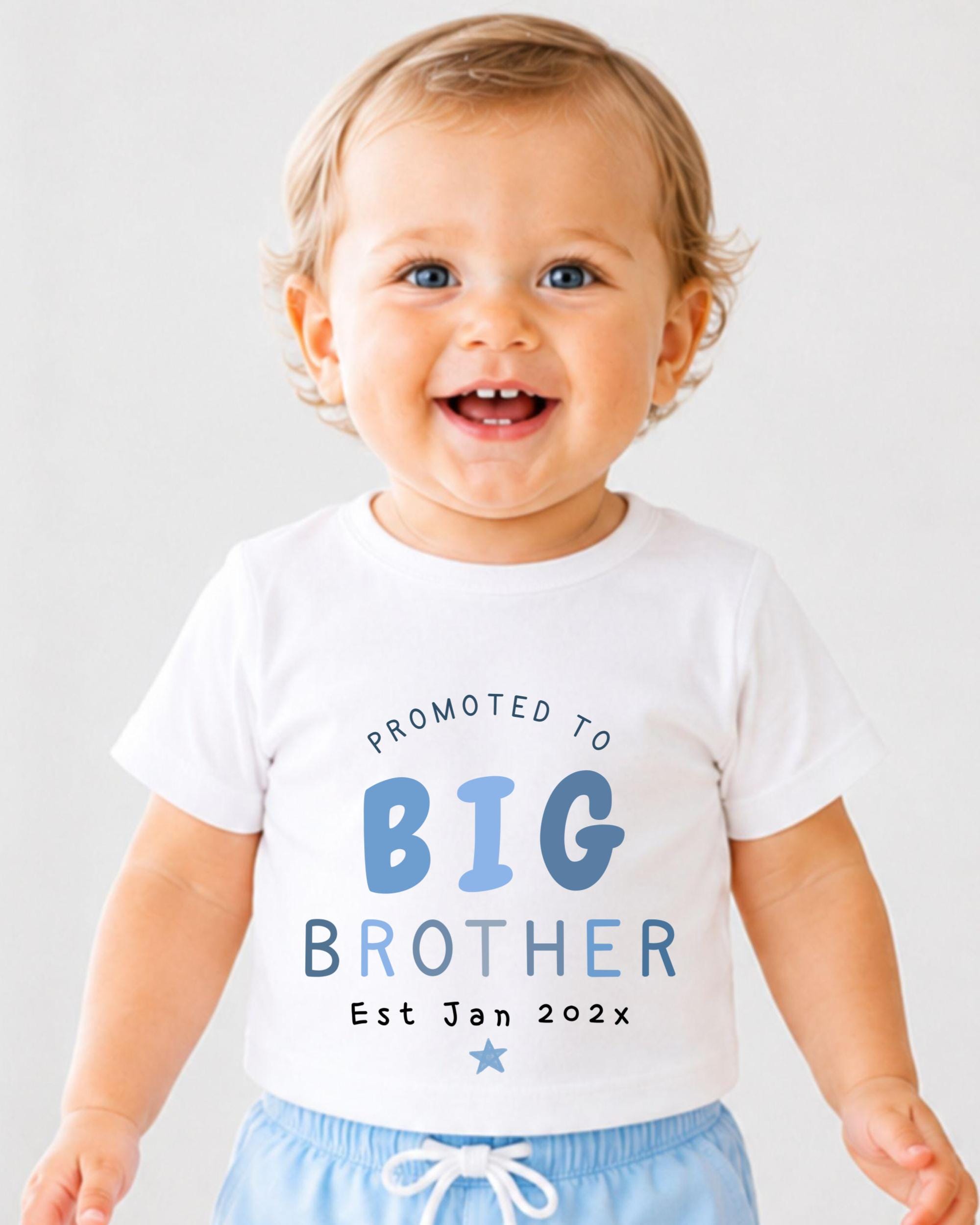 A smiling baby boy wearing a white t-shirt with text promoting a big brother announcement.