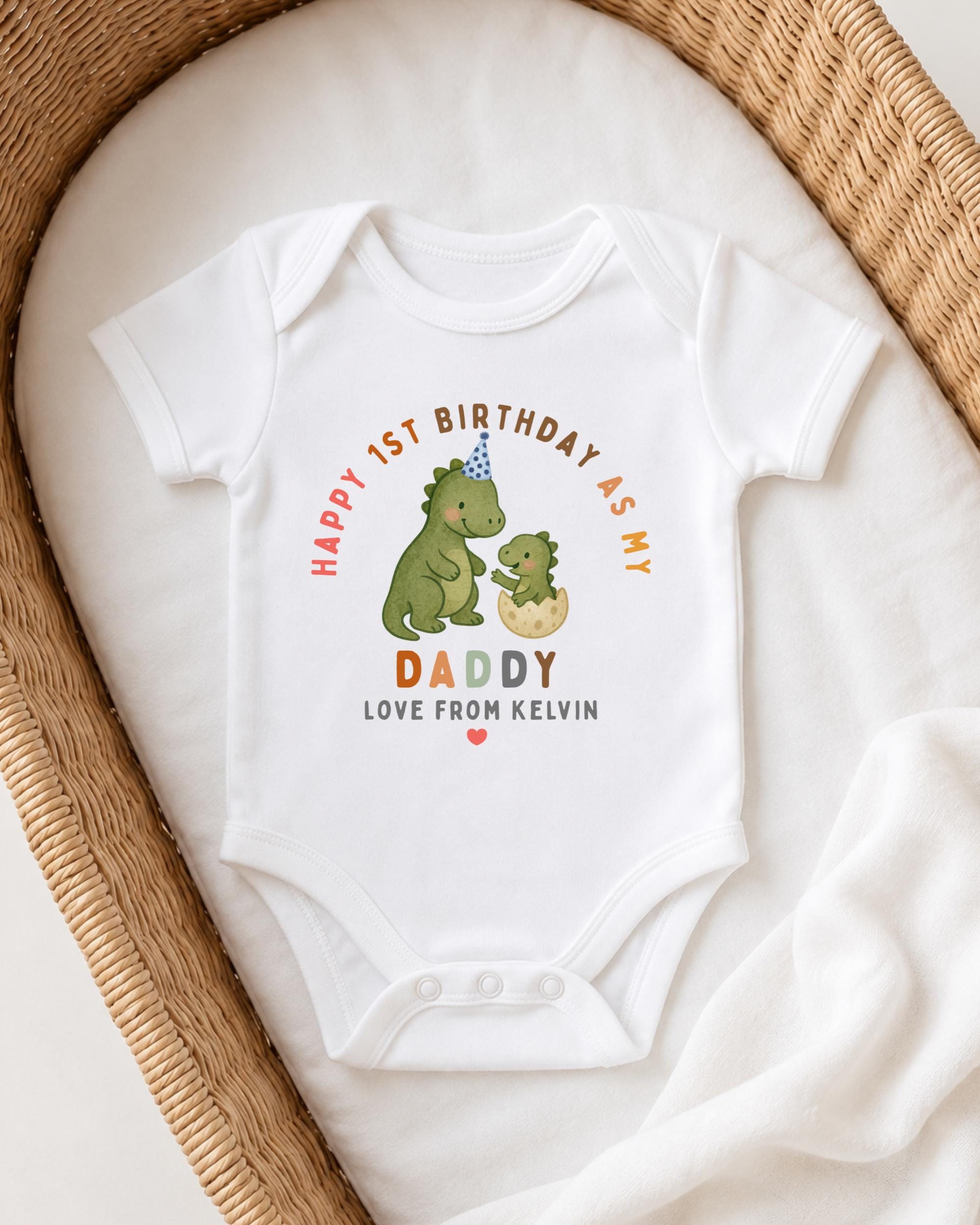 A white onesie with a dinosaur and a baby on it, placed on a white blanket.