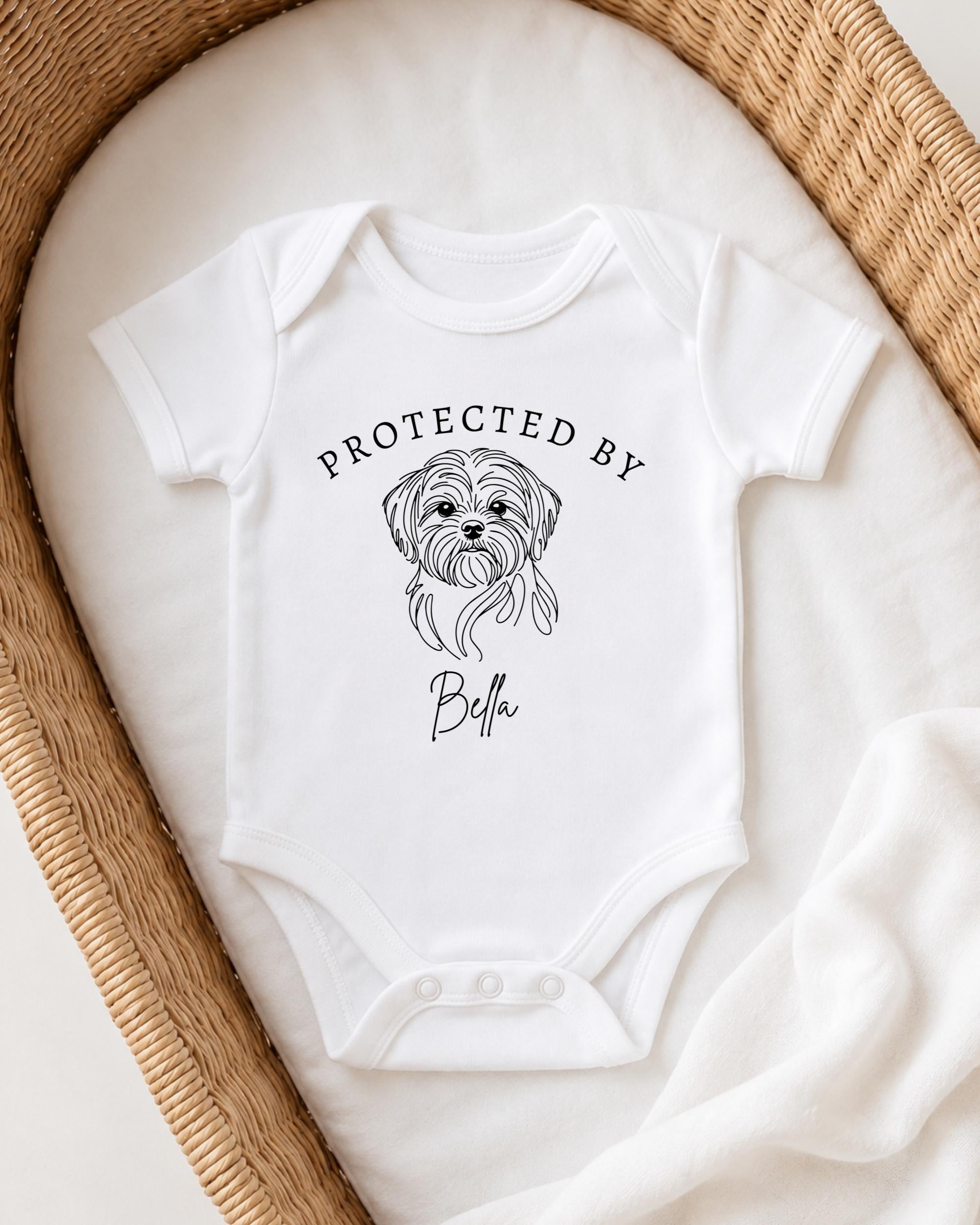 A white baby onesie with a graphic of a dog and the text "PROTECTED BY Bella" printed on it.