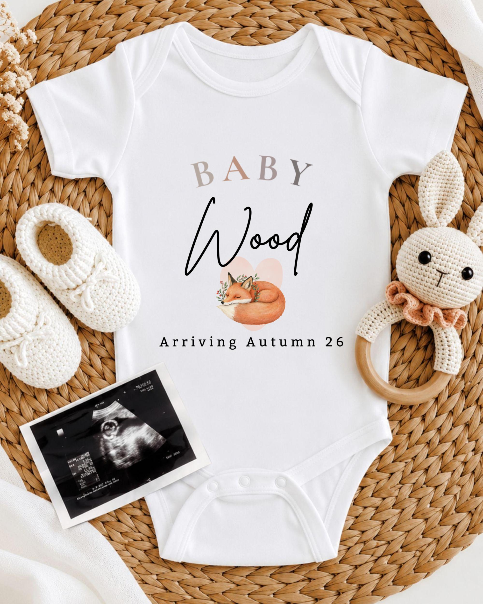 a baby onesie with the text "BABY Wood Arriving Autumn 26" printed on it, along with a crocheted rabbit toy and a baby bootie. There is also an Ultrasound image of a baby's belly.