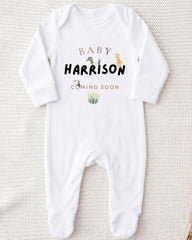 A white onesie with the text "BABY HARRISON COMING SOON" printed on it.