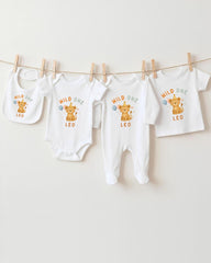 A collection of baby clothes, including onesies and bibs, hanging on a clothesline.