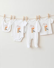 A collection of baby clothes, including onesies and bibs, hanging on a clothesline.