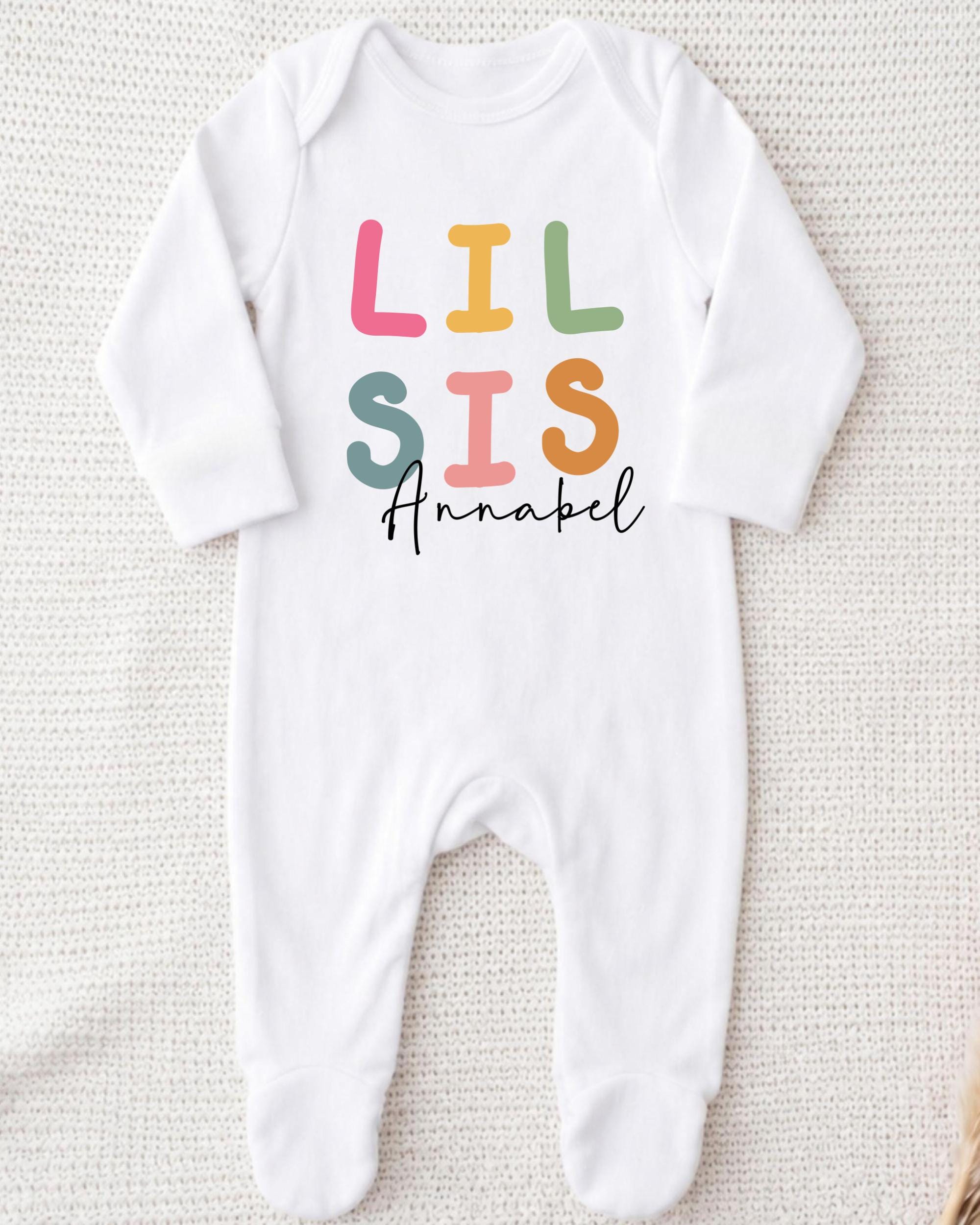A white onesie with the text "LIL SIS Annabel" printed on it.