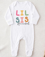 A white onesie with the text "LIL SIS Annabel" printed on it.