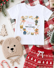 A white t-shirt with a Christmas-themed design, a beige knit hat, red and white patterned shorts, and various Christmas decorations such as a Christmas tree, ornaments, and a snowflake.