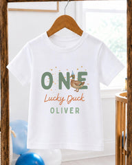 A white t-shirt with a graphic design featuring a cartoon duck and the text "One Lucky Duck Oliver" printed on it.