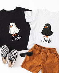 A black t-shirt with a ghost character, a white t-shirt with a black ghost character, a pair of brown shorts, and a pair of black and white checkered shoes.
