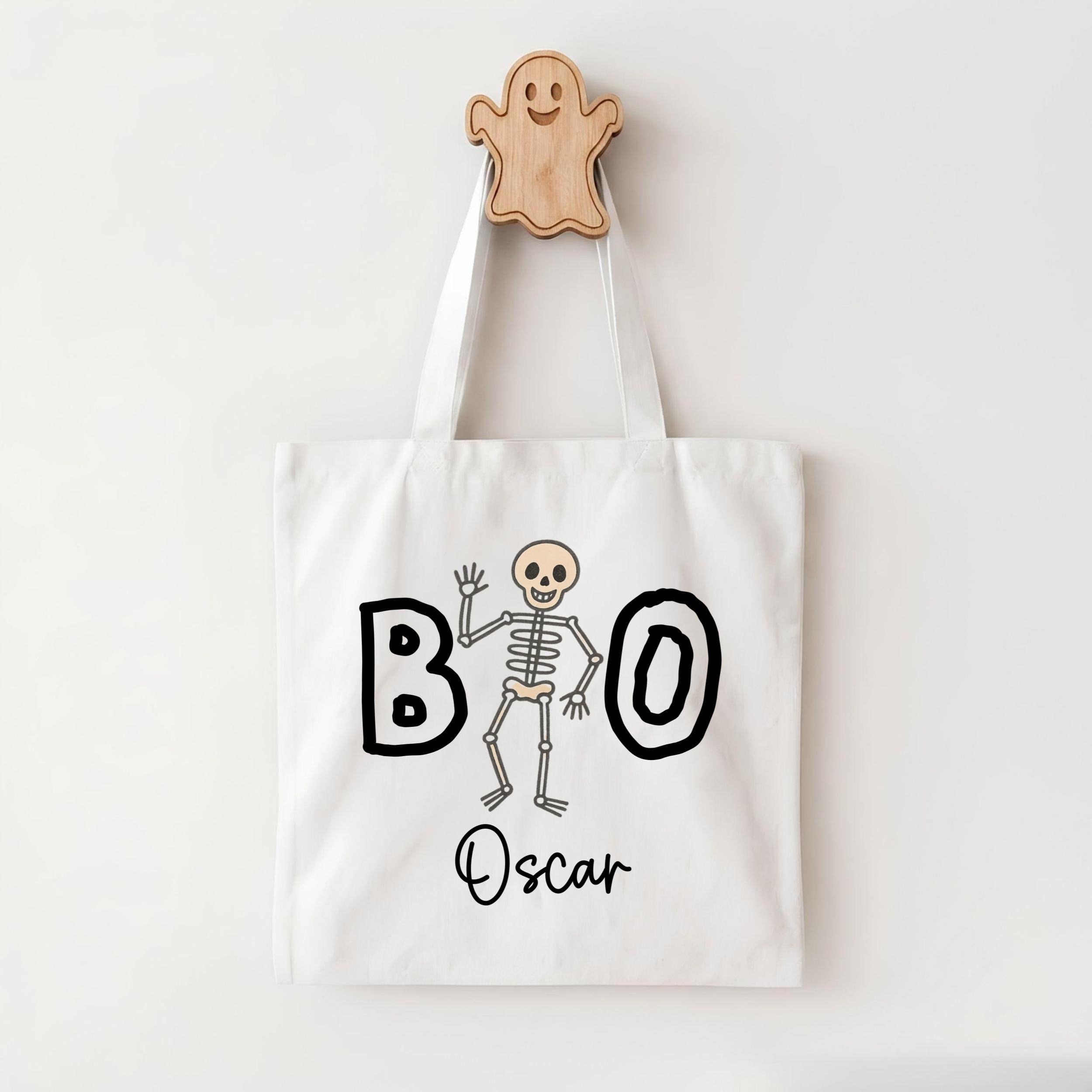 A white tote bag with a skeleton and the word "BOO" printed on it, along with the name "Oscar" below the skeleton.