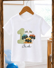 A white t-shirt with a graphic design featuring a green truck and two other trucks, along with a number 1 and a flag.