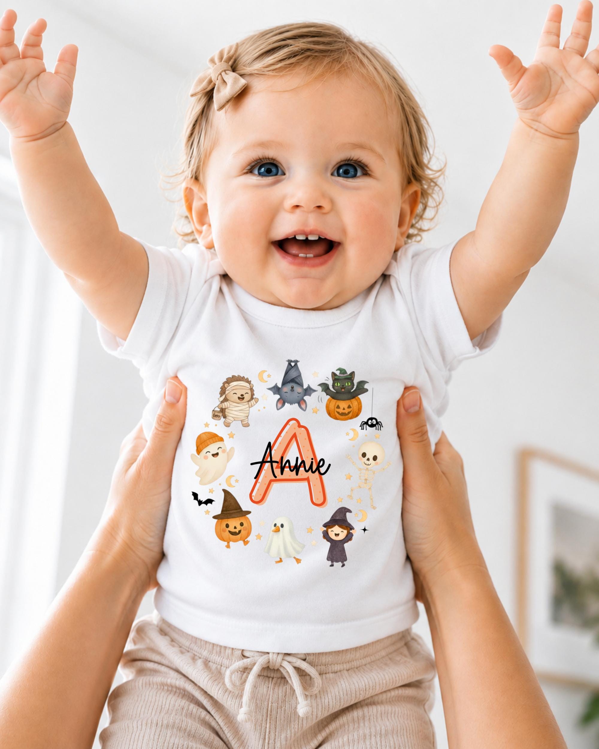 A smiling baby girl wearing a white t-shirt with a personalized name on it, surrounded by various cartoon animal characters.