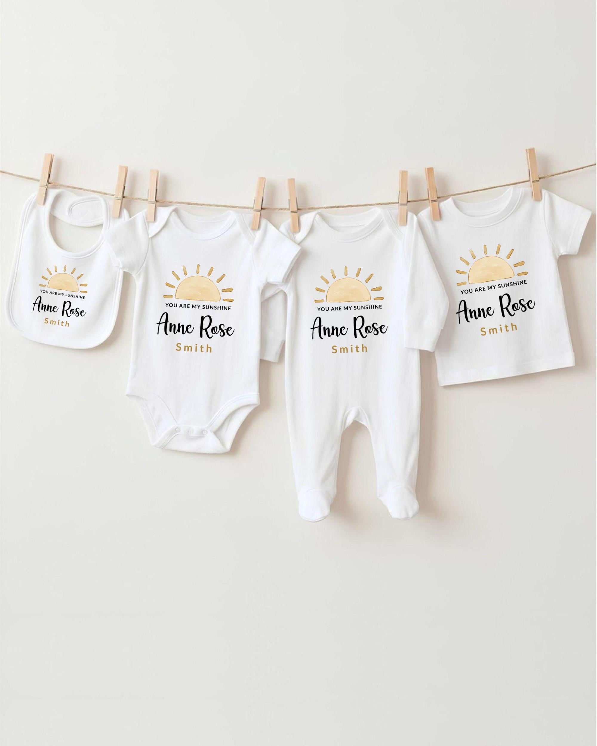 a collection of baby clothes, including onesies and bibs, hanging on a clothesline.
