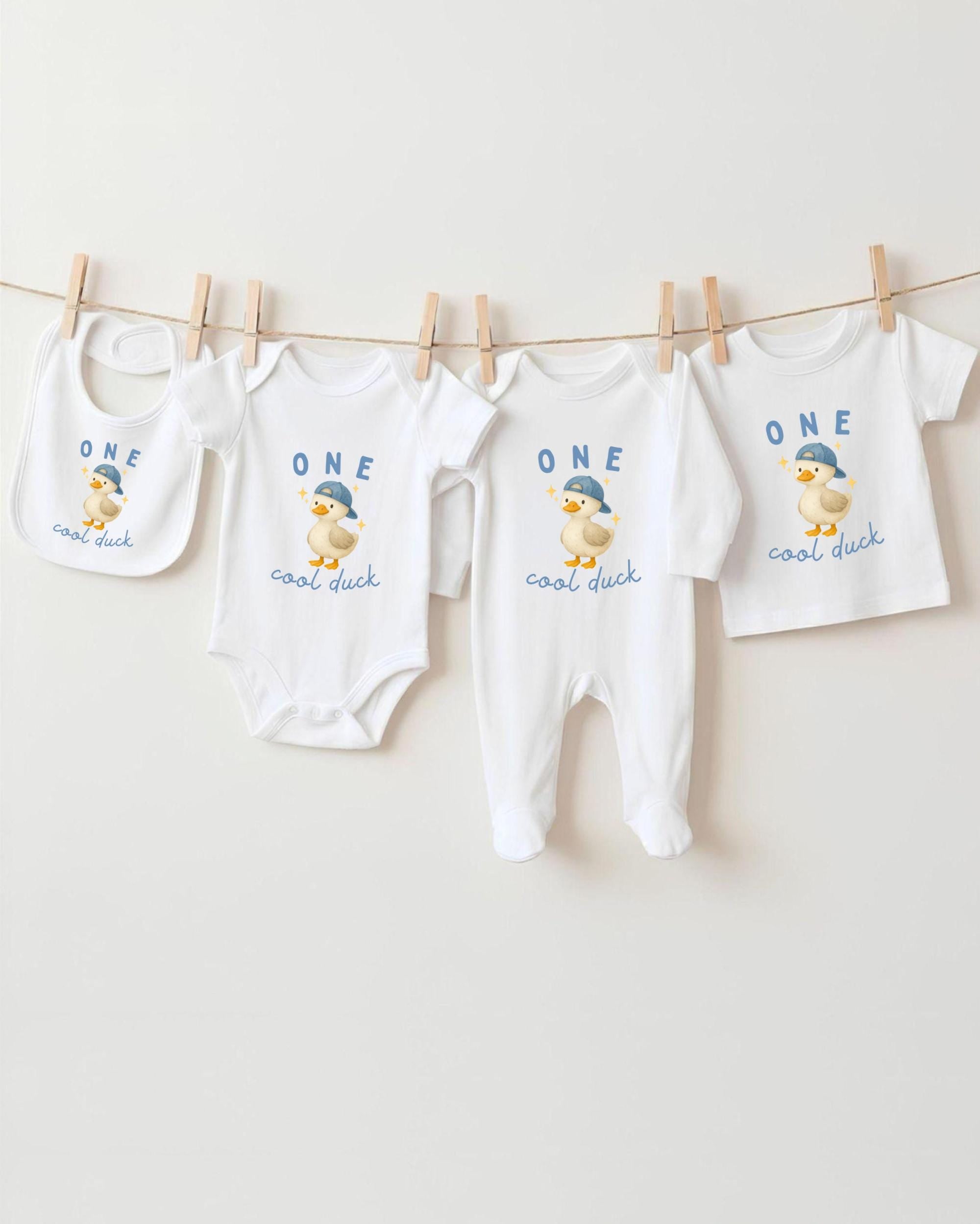 A collection of baby clothes, including onesies and bibs, hanging on a clothesline.