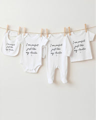 a collection of baby clothes hanging on a clothesline, with each piece featuring a unique message or description.