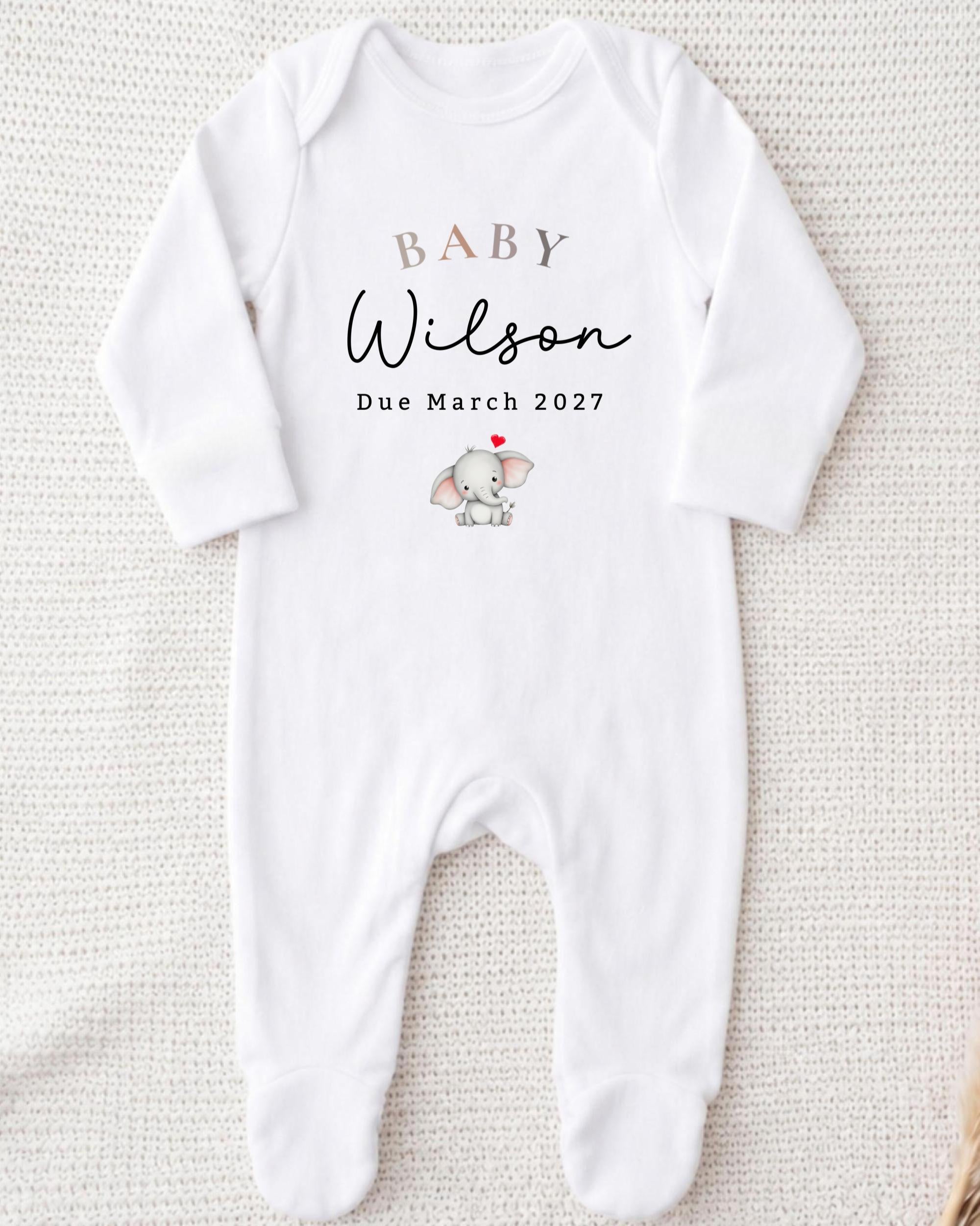 A white onesie with text and an image of a baby elephant printed on it.