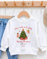 A white sweatshirt with a Christmas-themed design hanging on a wooden hanger.
