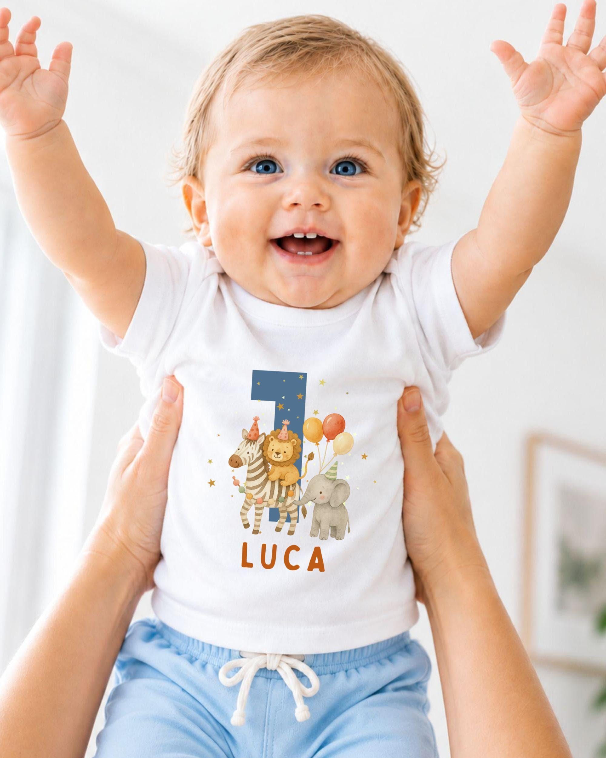 A smiling baby wearing a white t-shirt with a personalized number 1 and animal designs, being held up by someone's arms.
