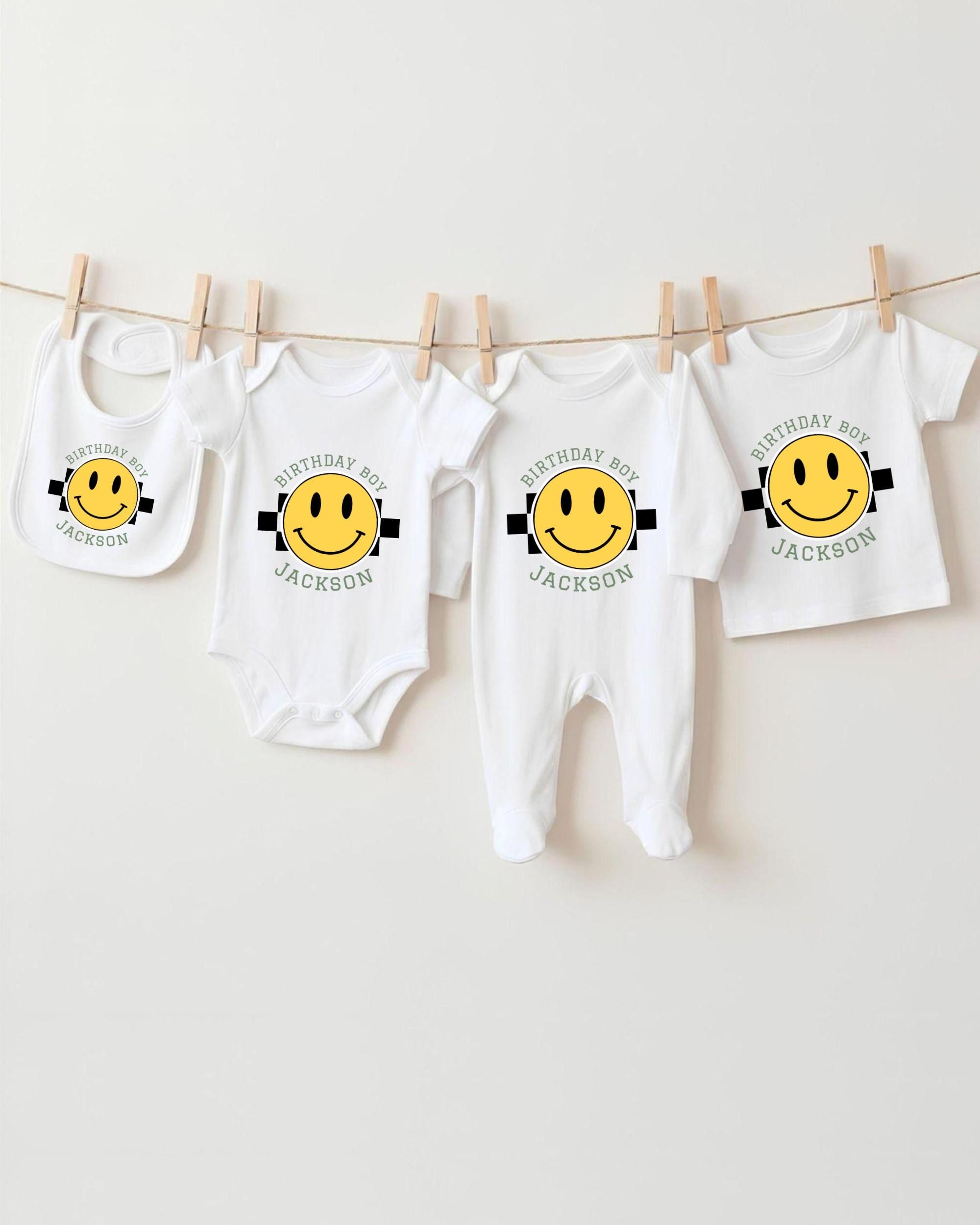 A collection of white baby clothes with yellow smiley faces printed on them, hanging on a clothesline.