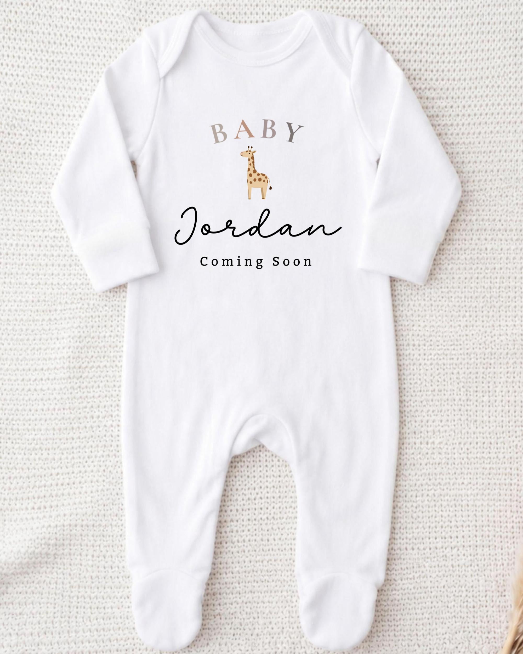 A white onesie with a giraffe design and text that says "BABY Jordan Coming Soon".