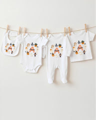 A collection of white baby clothes, including onesies and bibs, hanging on a clothesline.
