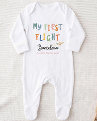 A white onesie with the text "My first flight Barcelona Custom month/year" printed on it.