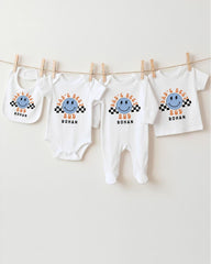 A collection of four white baby clothes, including onesies and bibs, hanging on a clothesline.