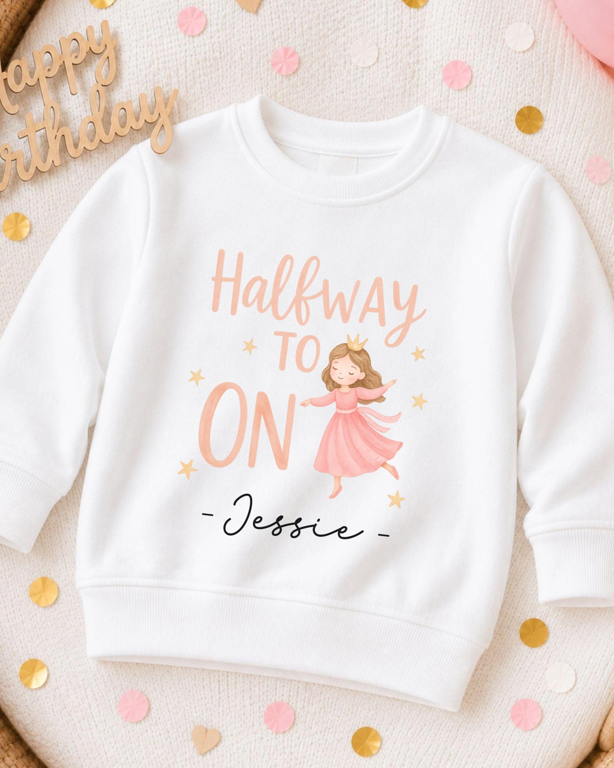 A white sweatshirt with a cartoon image of a girl wearing a pink dress and a crown, along with the text "Halfway to ON - Jessie" printed on it.