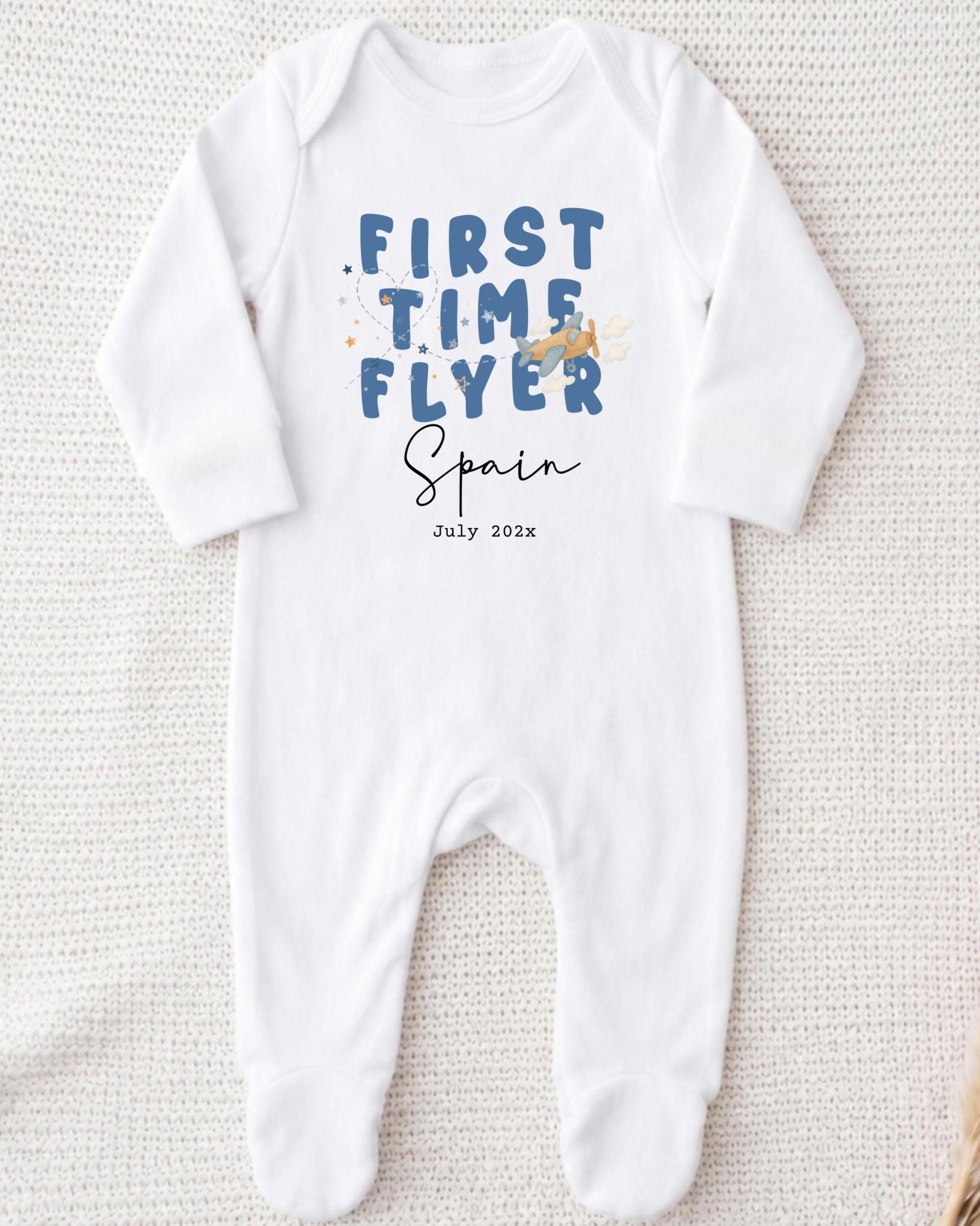 A white onesie with the text "FIRST TIME FLYER Spain July 2023" printed on it.