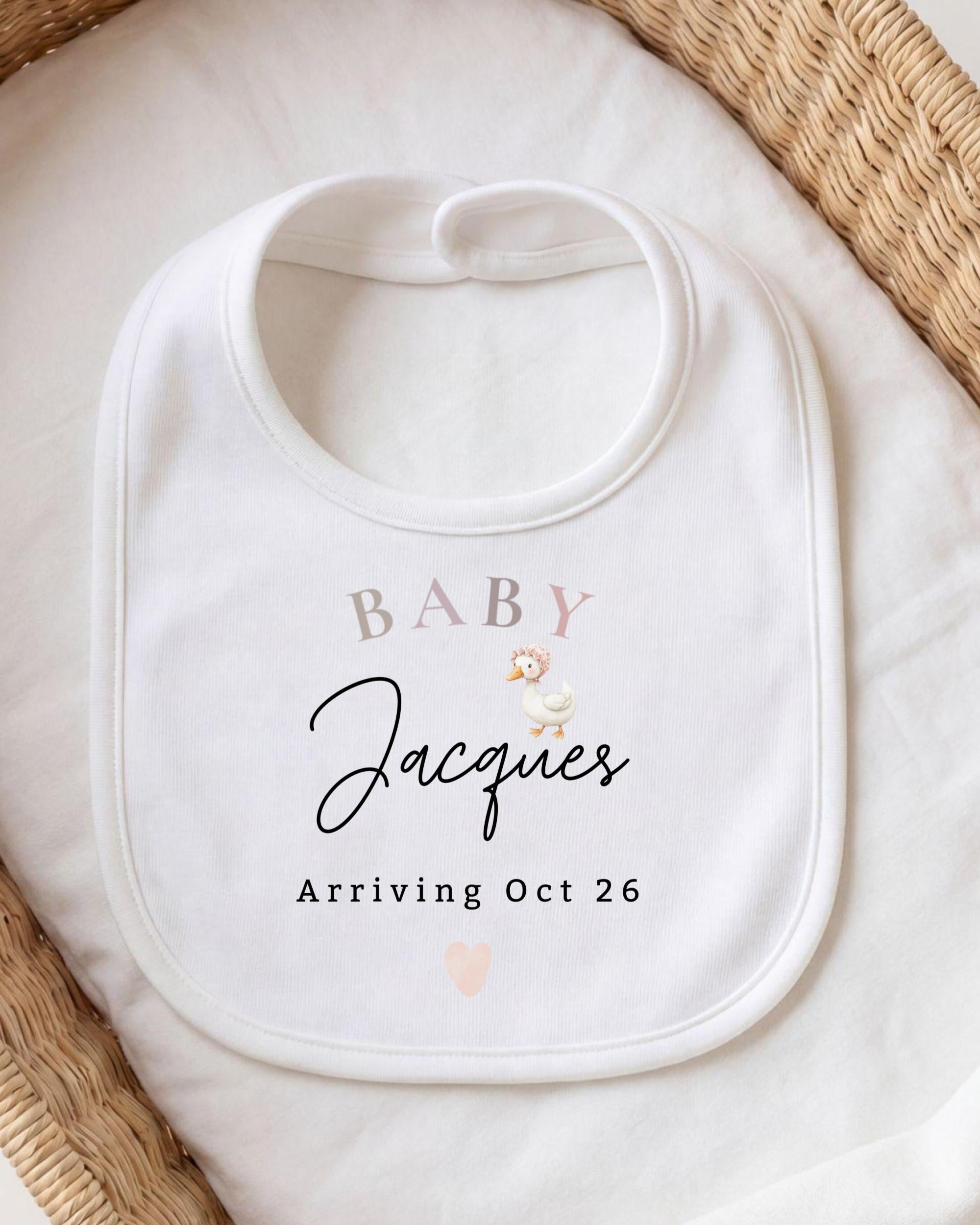A white baby bib with personalized text and a small illustration of a baby duck.