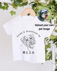 A white t-shirt with a black and white illustration of a dog and the text "Loved & Protected by Milo" printed on it.