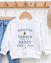 A white sweatshirt with the text "WATCHING TENNIS WITH MY DADY Daddy & Annie" printed on it, along with a small teddy bear graphic.