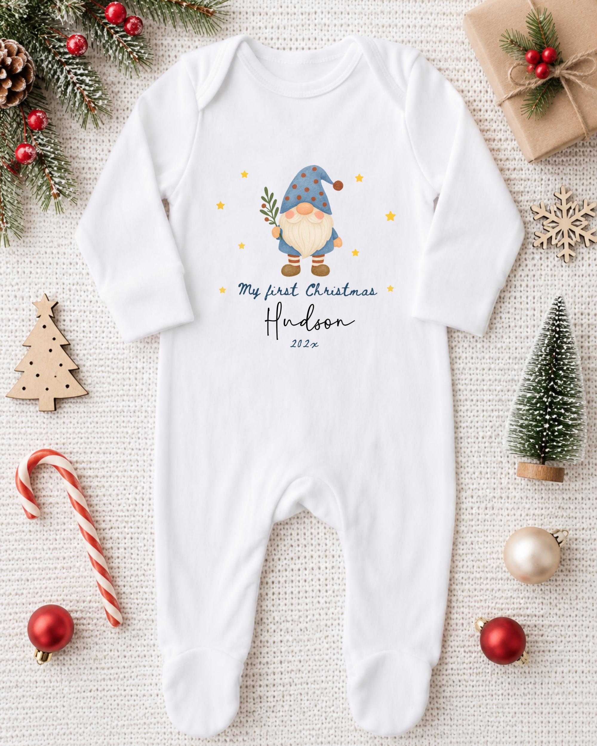 A white onesie with a gnome design and text, surrounded by Christmas decorations and ornaments.