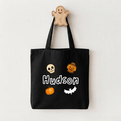 A black tote bag with Halloween-themed stickers and a wooden ghost hanger.