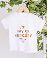 A white t-shirt with text and a teddy bear graphic, hanging on a wooden hanger.