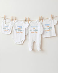 A row of white baby clothes, including onesies and bibs, hanging on a clothesline.