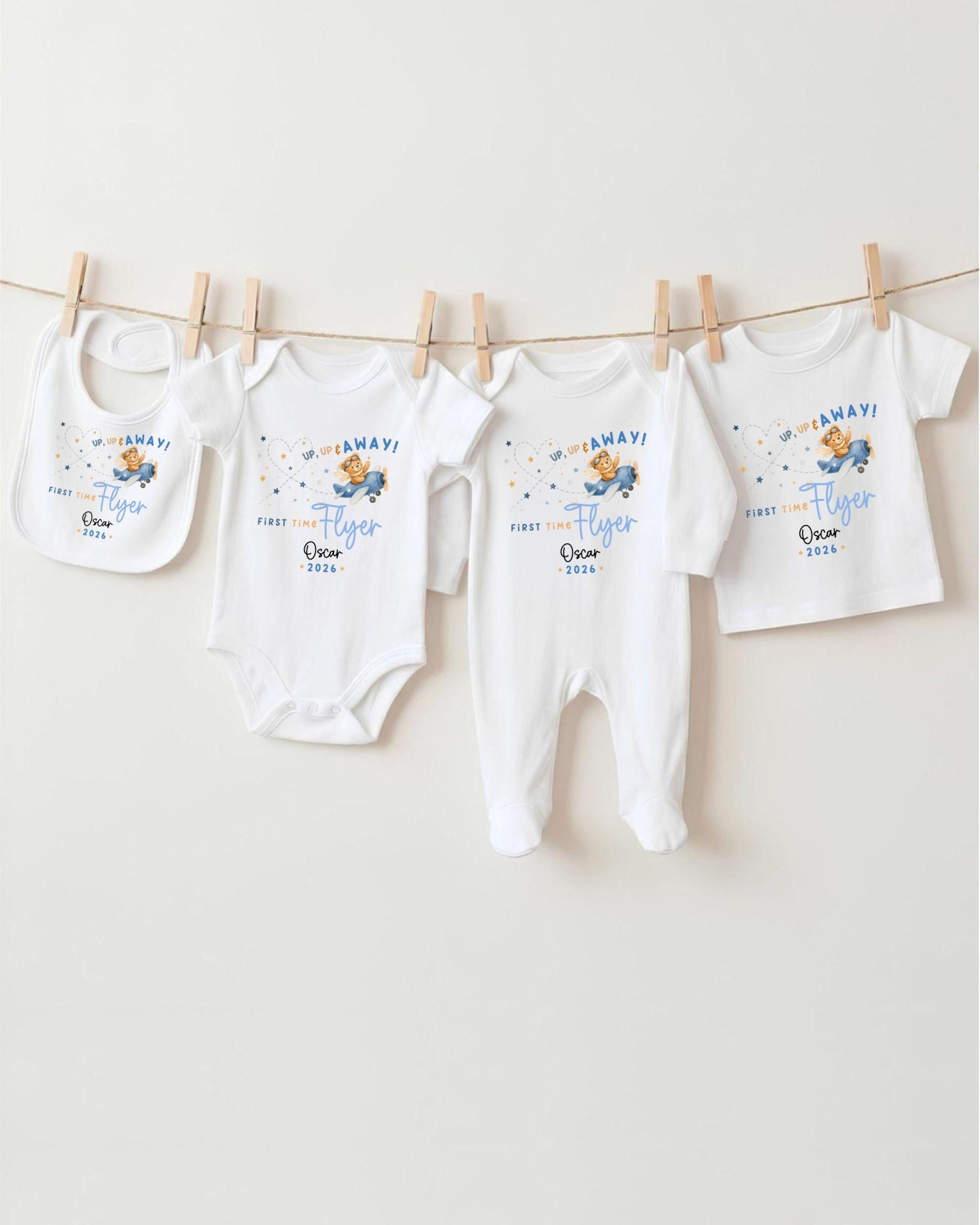 A row of white baby clothes, including onesies and bibs, hanging on a clothesline.