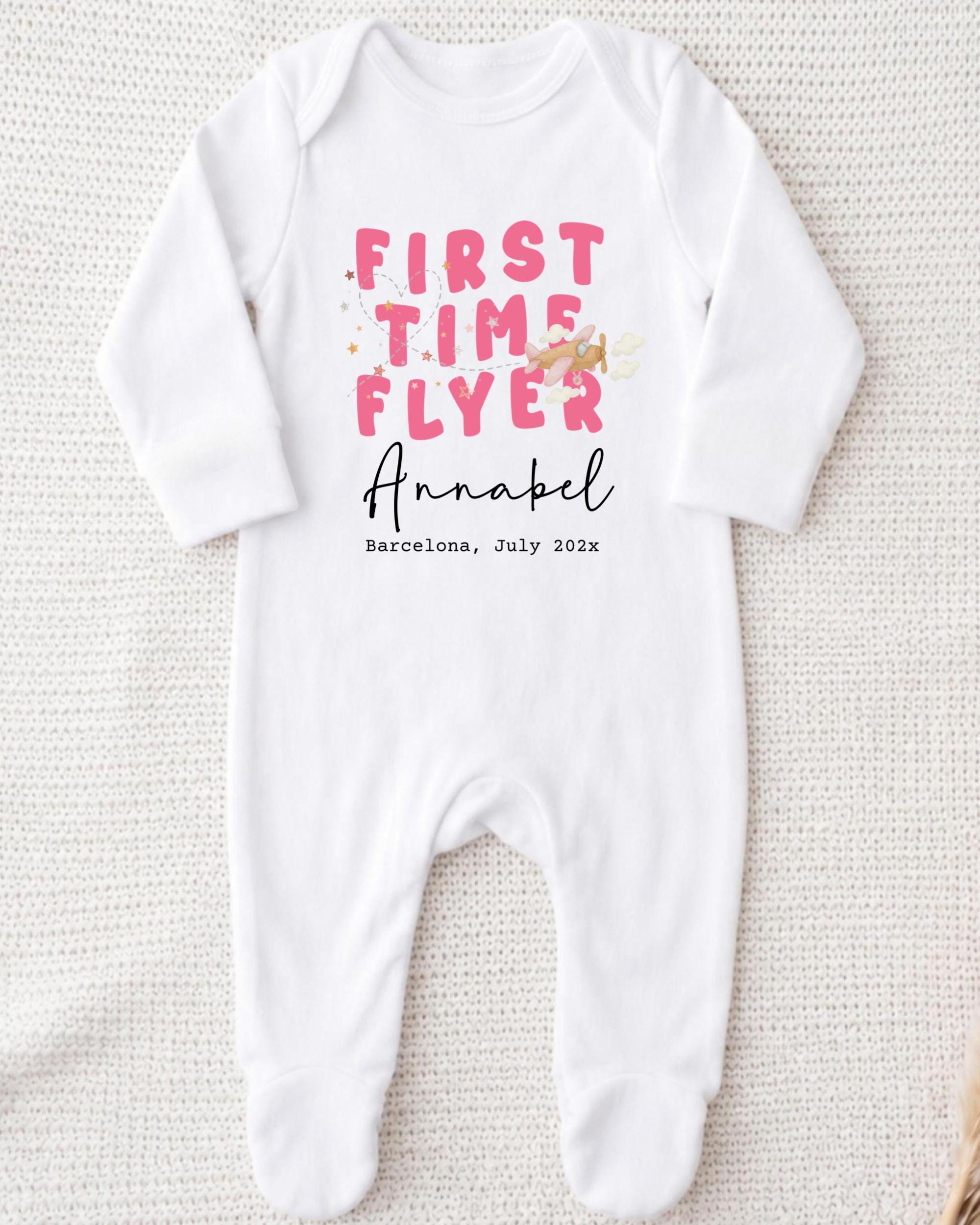 A white onesie with pink text and a small illustration of a bird on it.