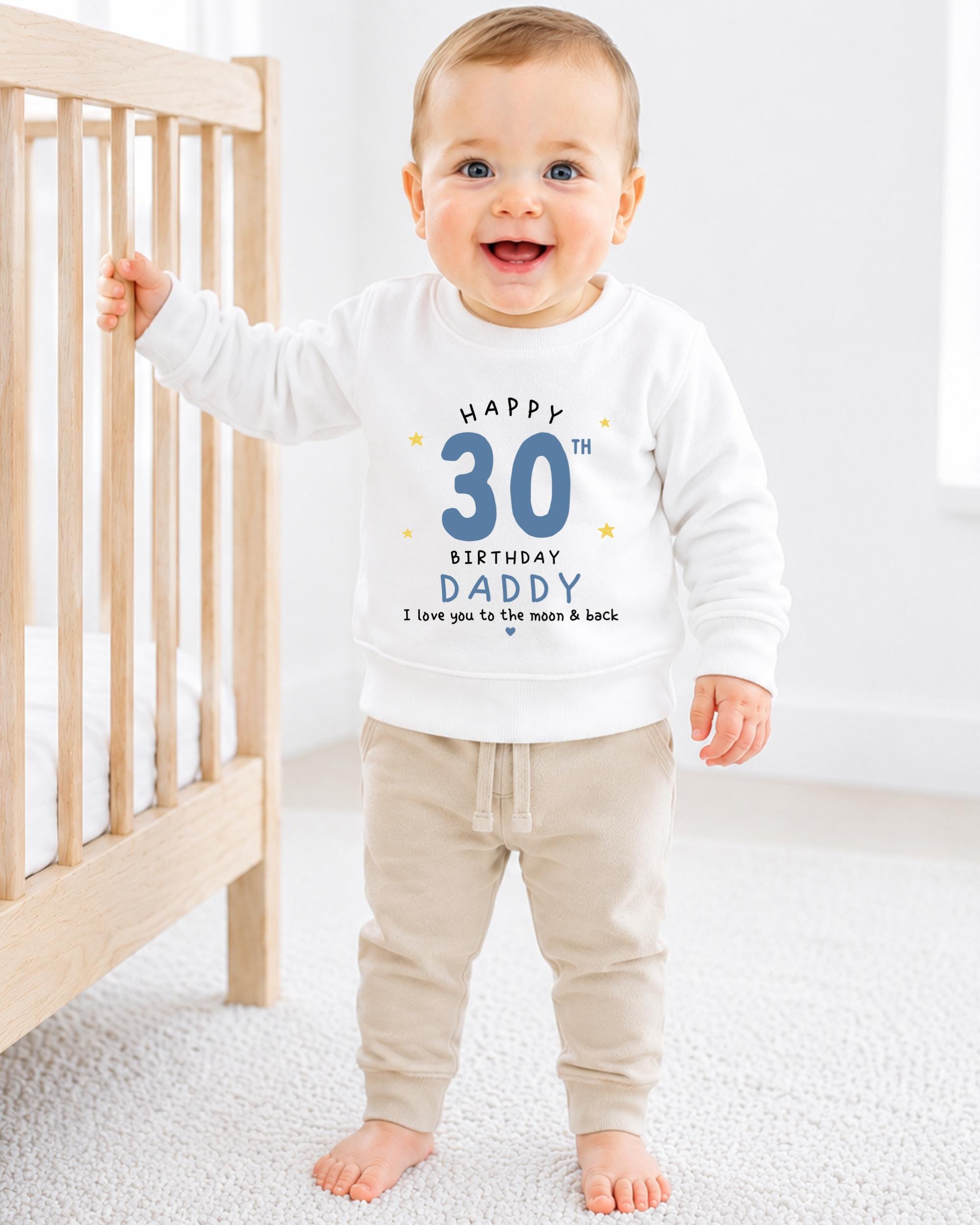 A smiling baby boy wearing a white sweatshirt with a birthday message and a number 30 on it.