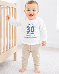 A smiling baby boy wearing a white sweatshirt with a birthday message and a number 30 on it.