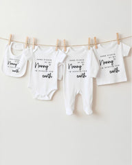 A row of four white baby clothes with black text, hanging on a clothesline.