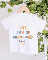 A white t-shirt with text and a small teddy bear graphic hanging on a wooden hanger.