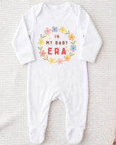 A white onesie with a floral design and text printed on it.