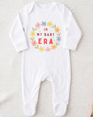 A white onesie with a floral design and text printed on it.