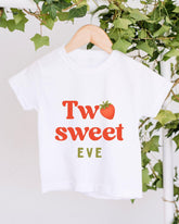 A white t-shirt with the text "Two sweet Eve" printed on it, along with a red strawberry graphic.